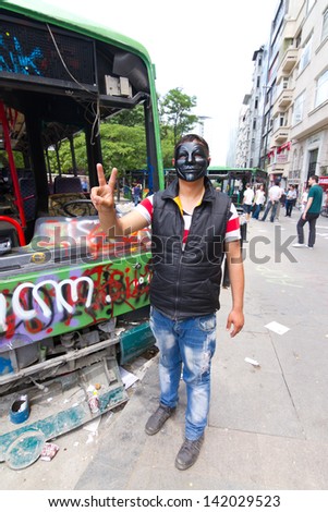 ISTANBUL - JUNE 08: Man with mask in front of damaged bus during protests on June 08, 2013 in Istanbul, Turkey. Guy Fawkes masks widely used and became a symbol of protests in Turkey.