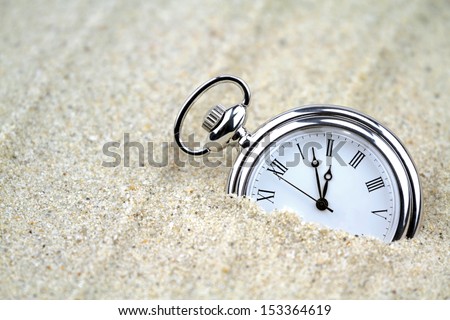 Pocket watch semi buried in the sand