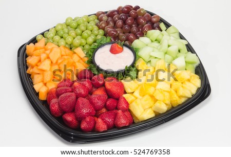Party platter of fresh fruit: strawberry, cantaloupe, pineapple, grapes and melon served with small bowl of yogurt dip in middle - shot on white background. ストックフォト © 