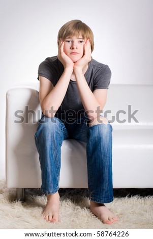 Calm redhead teenager sitting on white sofa