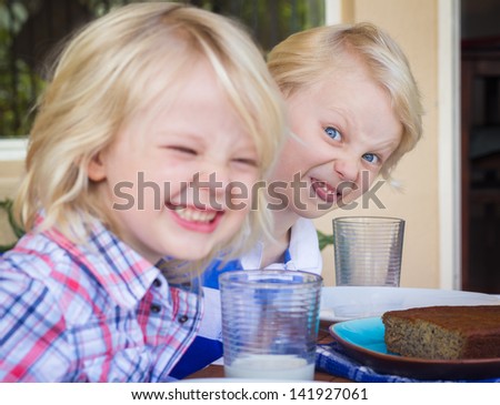 Funny photo of two children eating with bad manners. One child is poking out his tongue.