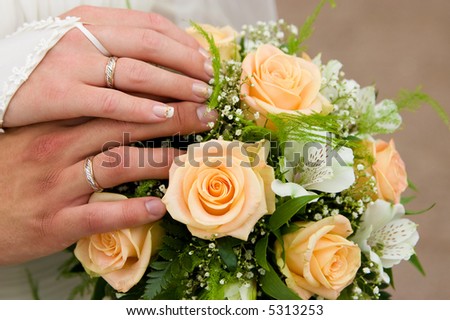 Married couple holding hands on a wedding bouquet