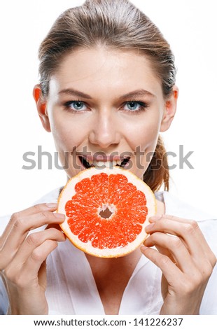 Young beautiful woman eat grapefruit / good looking girl of the european appearance biting a cut piece of grapefruit - isolated on white background
