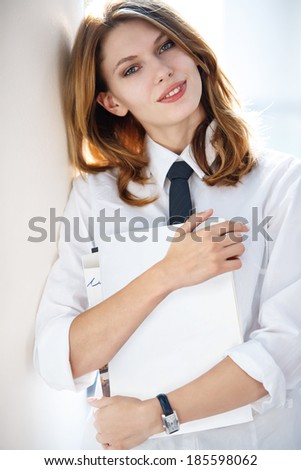 Young woman holding folders / attractive student teacher wearing a white button down shirt and a tie