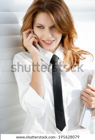 Business woman holding folder in her hand and talking on the phone / talkative woman in a white button down shirt with black tie