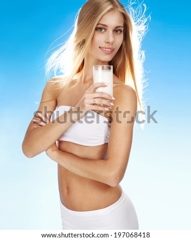 Healthy lifestyle / portrait of happy smiling girl with transparent glass of milk in her hand on blue background