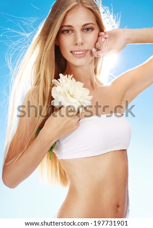 Charming woman / portrait of happy smiling girl with white flower in her hand on blue background
