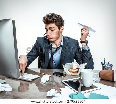 Young office man with paper plane in his hand typing on a computer keyboard / modern office man at working place, sloth and laziness concept