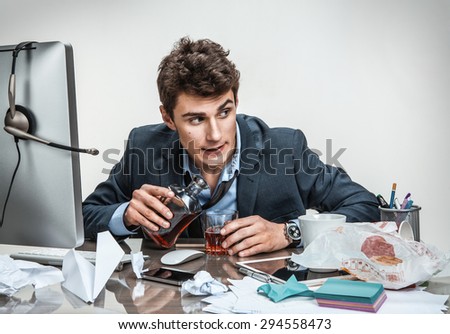 Drunk businessman sitting drunk at office with computer holding glass looking depressed wearing loose tie in alcohol addiction problem concept