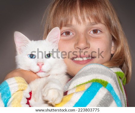 Happy smiling girl is hugging a white kitten.