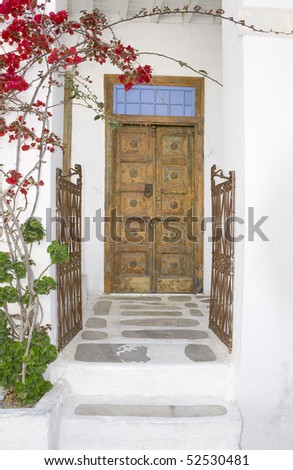 Wooden door and an old iron gate with blooming bougainvilleas