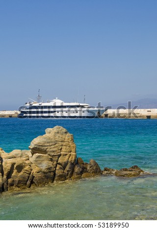 White-blue yacht docked in the port of the island not far offshore boulders