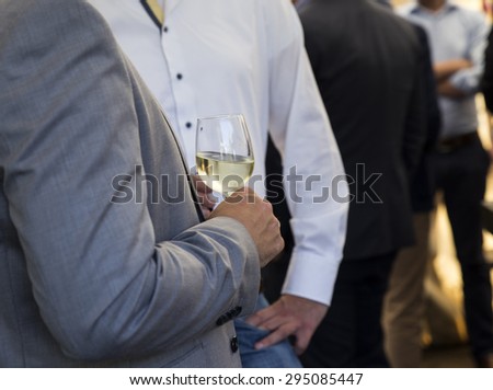Man in suit drinking glass of white wine at party