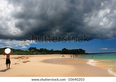 Surfer getting ready for a powerful storm above Makena beach in Hawaii