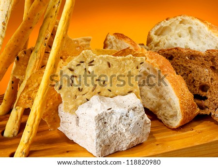 Original wooden plate with different types of bread, chips with cumin and salt, bread sticks