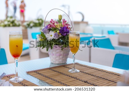Alcoholic drink with fruit juice in glass. Blur beautiful bouquet of flowers.