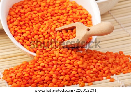 dry red lentils in a wooden spoon macro on the table horizontal