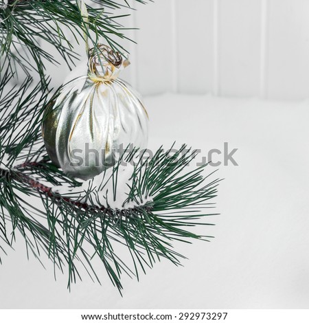 Authentic pine branch in the snow decorated Christmas baubles, selective soft focus as a background for a Christmas design.