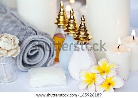 Three Plumeria flower with massage oil and balsam in bowl , towel and candle