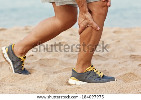 Cramps in leg calves or sprain calf on triathlete runner. Sports injury concept with running man.