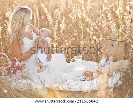 Happy family on sunset. Mother in white dress with baby in nature