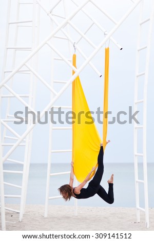 Young woman doing yoga exercise. Yoga with hammock. Anti gravity yoga. Yoga by the sea.