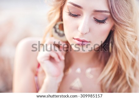 Fashion portrait of elegant woman with magnificent hair. Blond Girl in elegant dress. Flash tattoo gold