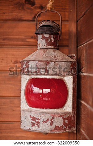 Rusty lit red lantern hanging in an old shed