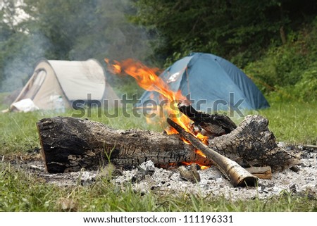 Camp Fire and two tents in the background