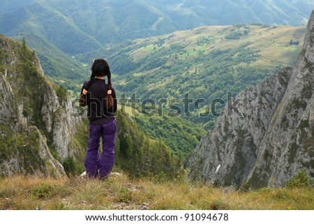 a young girl admiring mountain view on the brink