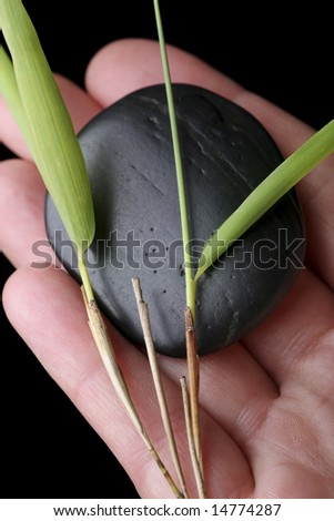 single massage stone in hand with bamboo