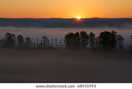Bulgarian sunrise with fog on a tree valley