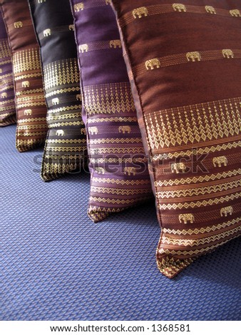 Close up of brown, purple, and black cushions on a blue couch.