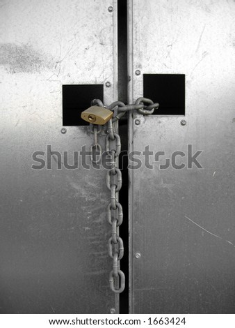 A closed silver metallic gate locked with an iron chain and padlock
