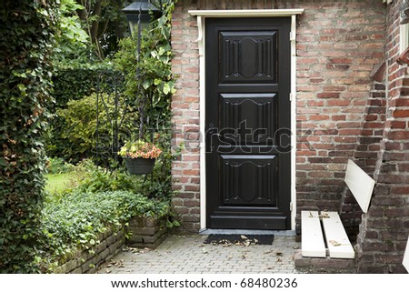 Old door to brick building with garden and flowers.