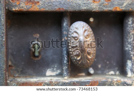 Closeup of metal doorknob and keyhole in rusting metal gate.