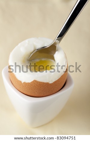 Soft boiled egg in egg cup with spoon.