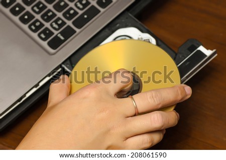 hand holding dvd insert to notebook computer