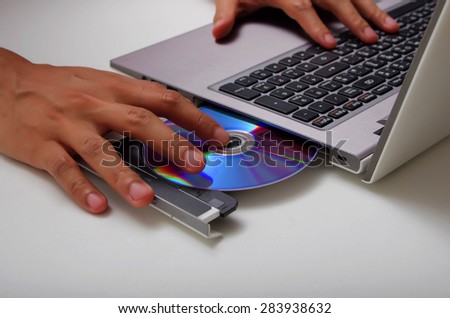 hand holding dvd insert to notebook laptop computer