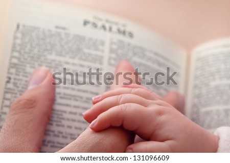 Baby holding father\'??s finger as he points to Psalms verse