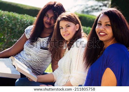Three Christian girls studying the Bible and looking at the camera