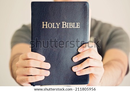 Close up of a young man proudly holding out his Bible