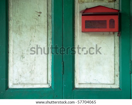 red mail box on green wood door