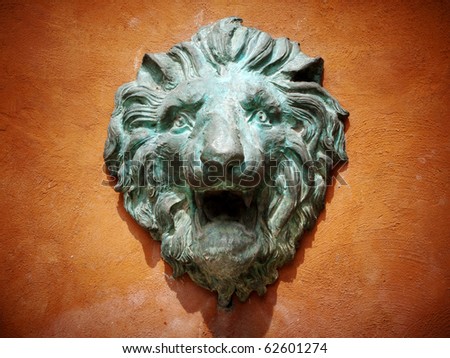 Cast green metal lion head on the orange wall