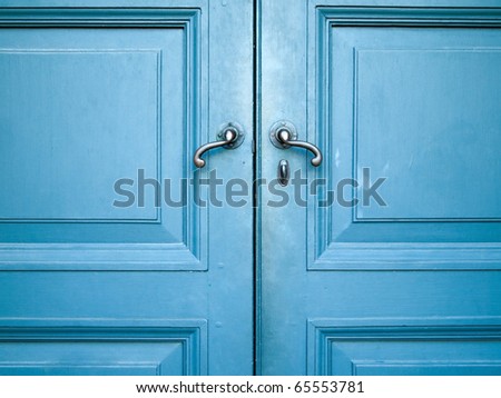 Door handles with an old double wood door painted with blue