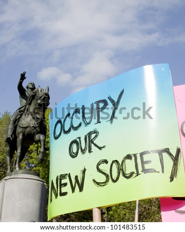 NEW YORK - MAY 1: A sign that reads \'Occupy Our New Society\' is displayed in front of a statue of George Washington during May Day protests in Union Square on May 1, 2012 in New York, NY.