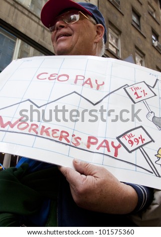 NEW YORK - MAY 1: A protester holds a sign that compares workers pay to CEO pay during the march to Union Square from Bryant Park at Occupy Wall St \'May Day\' protests on May 1, 2012 in New York, NY.