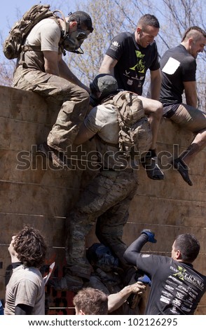 POCONO, PA - APR 29: A participant gets help to get up and over the Berlin Walls obstacle at Tough Mudder on April 29, 2012 in Pocono Manor, PA.  The course is designed by British Special Forces.