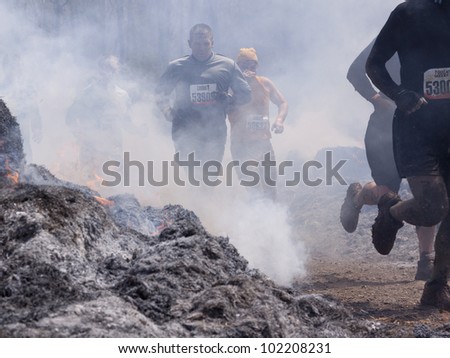 POCONO MANOR, PA - APR 28: A group of men runs through the Fire Walker obstacle at Tough Mudder on April 28, 2012 in Pocono Manor, Pennsylvania. The course is designed by British Royal troops.