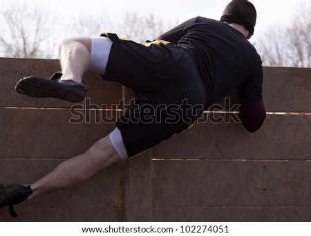 POCONO MANOR, PA - APR 28: A man lifts himself over a wooden wall at the starting line at Tough Mudder on April 28, 2012 in Pocono Manor, Pennsylvania. The course is designed by British Royal troops.